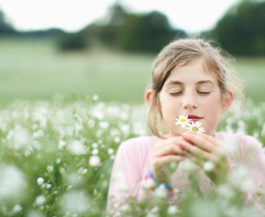 Girl smelling flowers in meadow