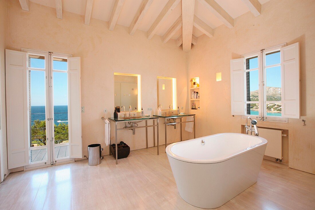 Freistehende Badewanne unter Holzbalkenedecke im minimalistischen Bad mit Meerblick