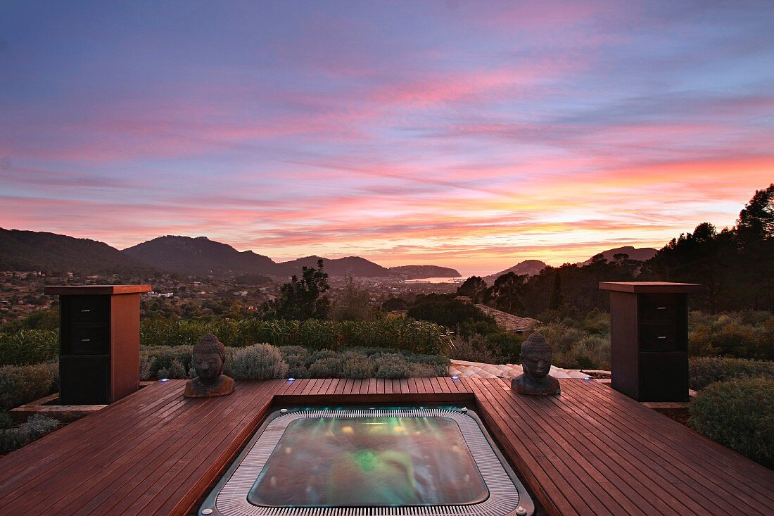 Hot tub surrounded by wooden deck at sunset
