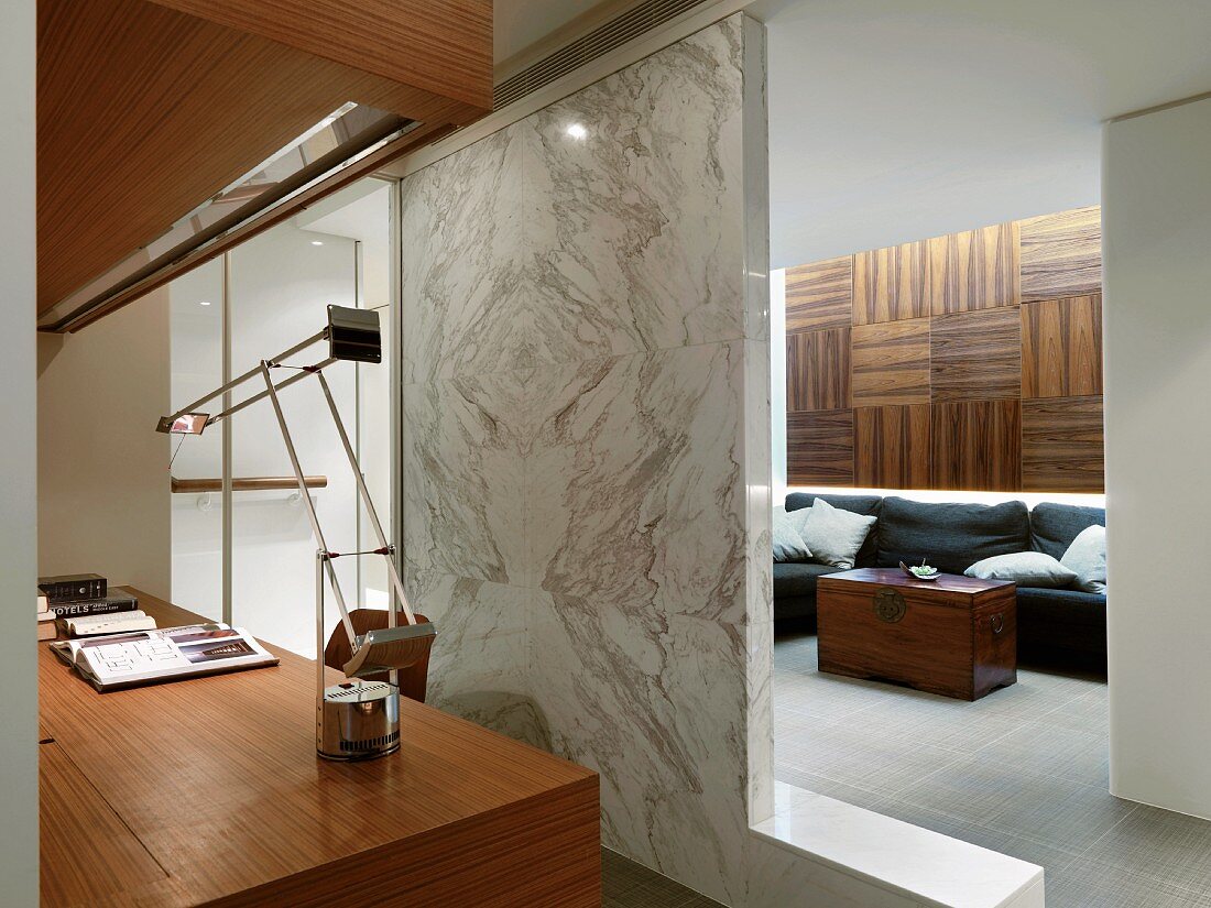 Marmorwand als Raumteiler zwischen holzvertäfeltem Wohnraum und Home Office