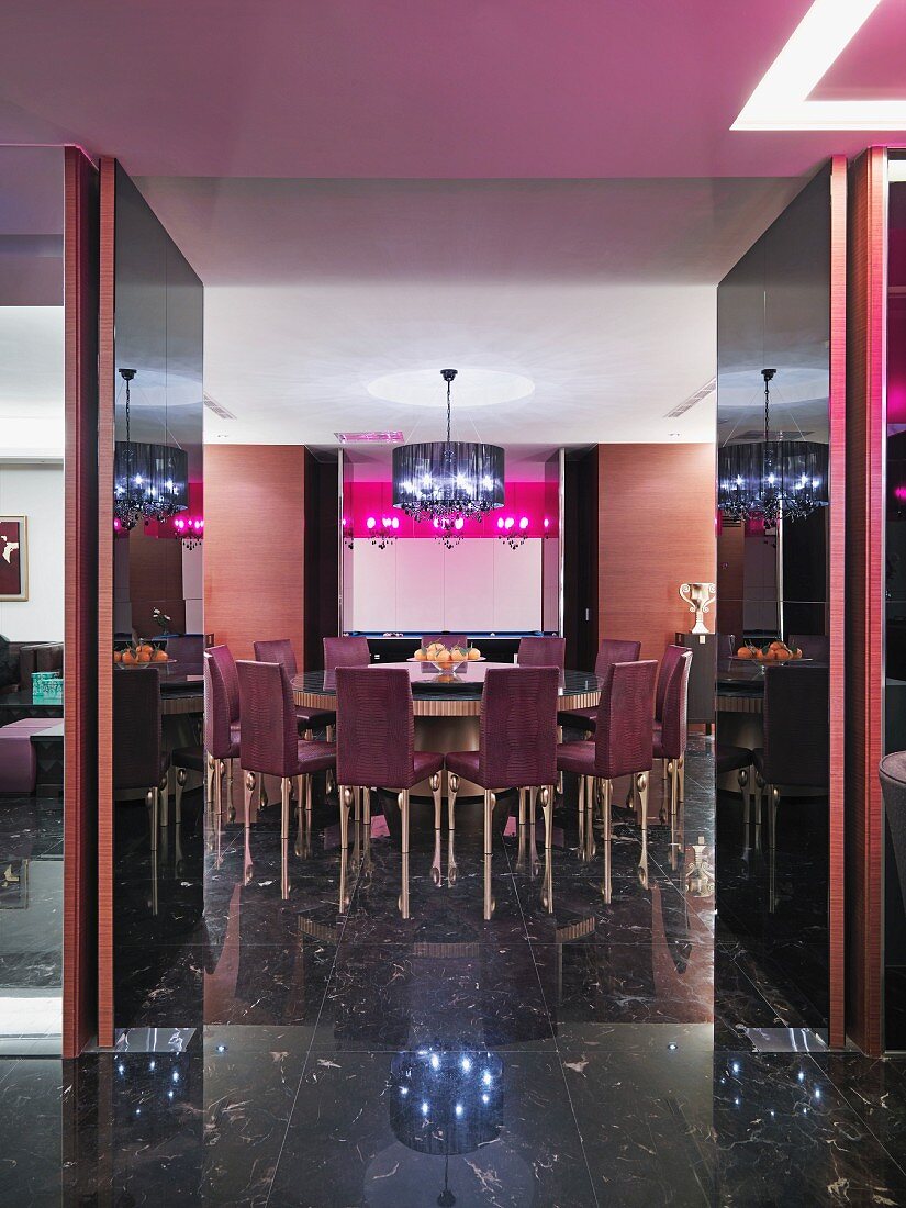Blick durch geöffnete Flügeltüren auf runden Tisch in eleganter Lounge mit dunklem Marmorboden
