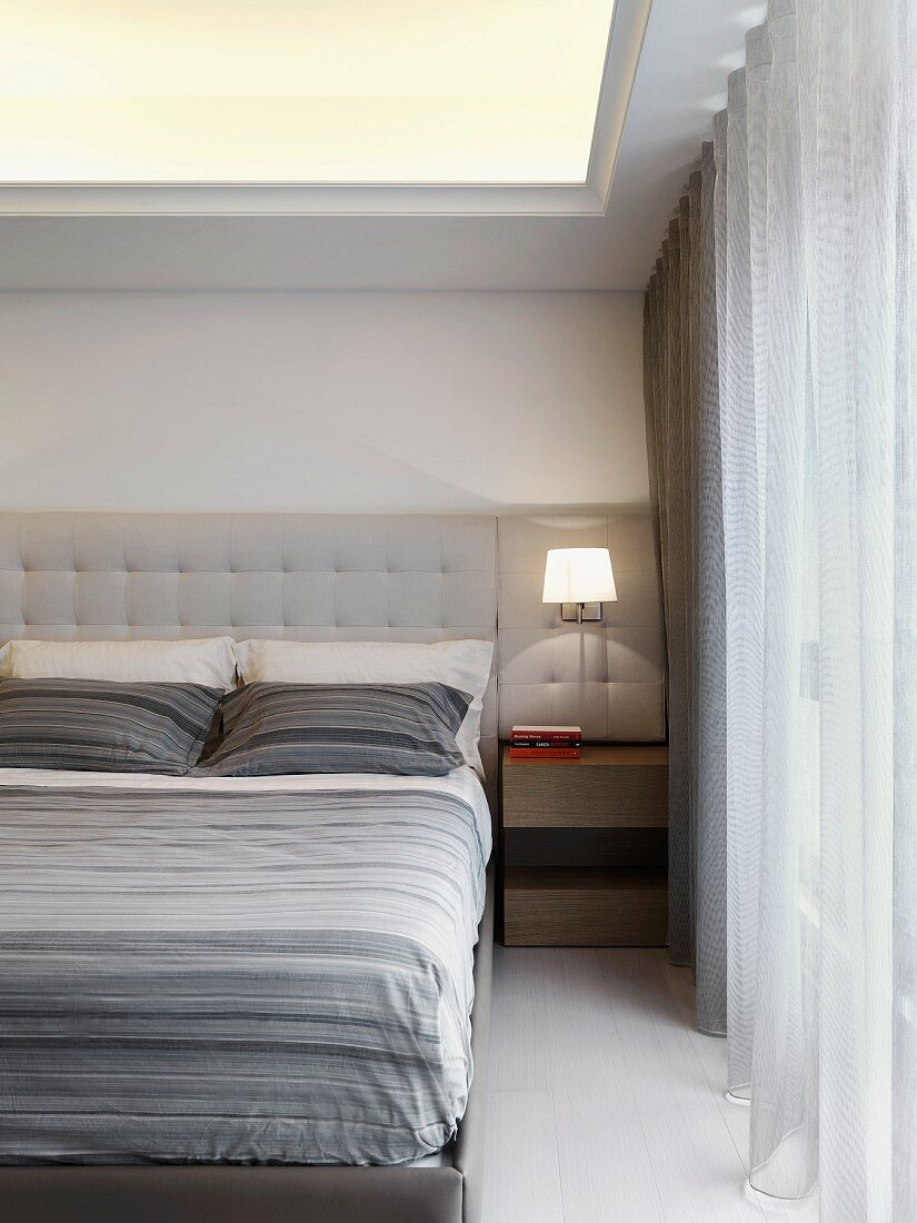 Doppelbett mit gepolstertem Kopfteil und grau gestreifter Bettwäsche in klassisch modernem Schlafzimmer