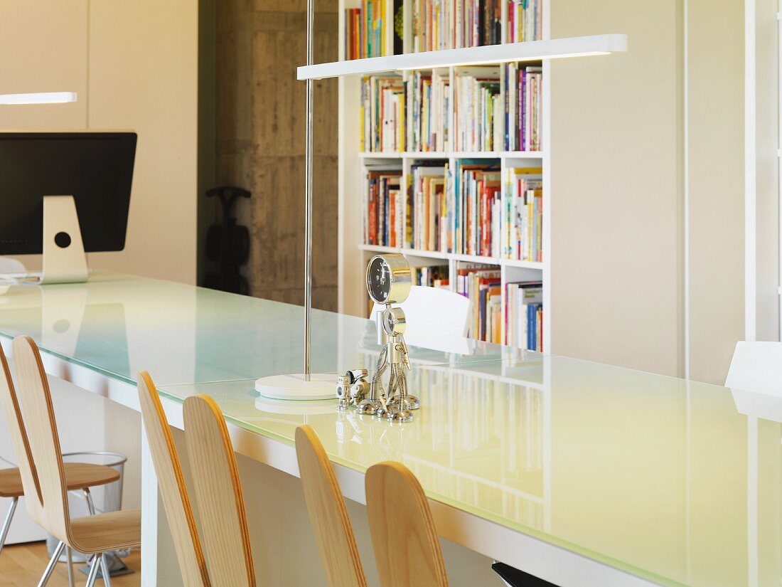 Lange Tafel mit Glasplatte und Designerstühlen in modernem, weißem Büroambiente