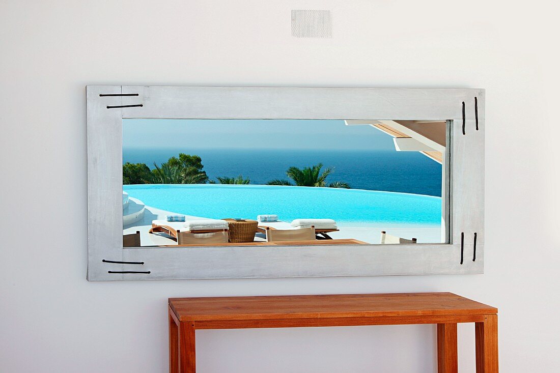 Schlichter Holztisch am Fenster mit Blick auf Pool und Meer