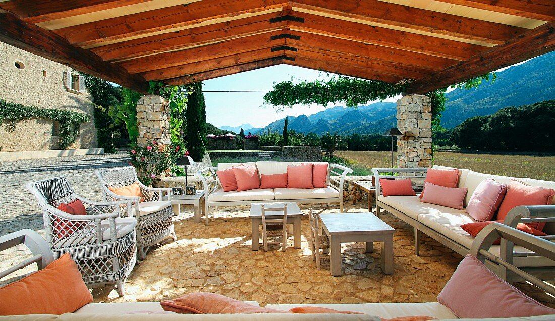 Überdachte Terrasse mit Sofagarnitur und Korbstühlen auf Natursteinboden