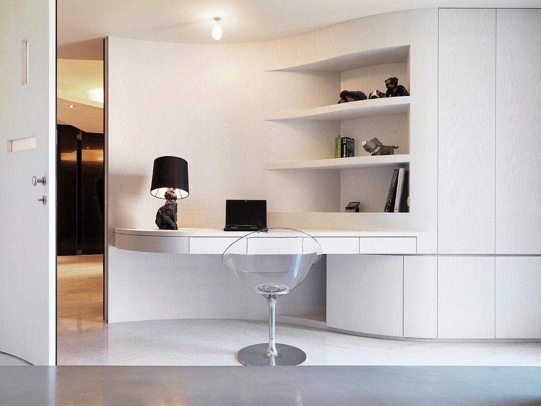 Transparenter Schalenstuhl vor weißem Multifunktions - Raumteiler mit Arbeitsplatte und Regal