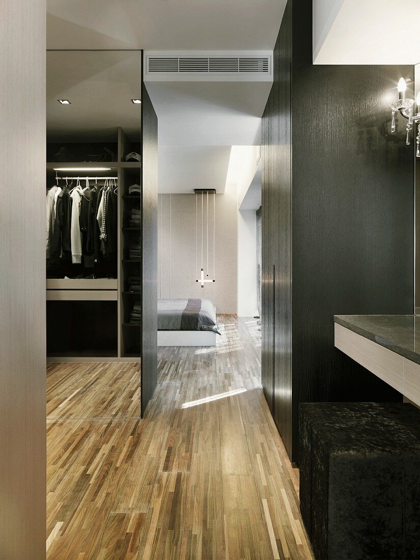 Modern closet with parquet flooring next to a bedroom
