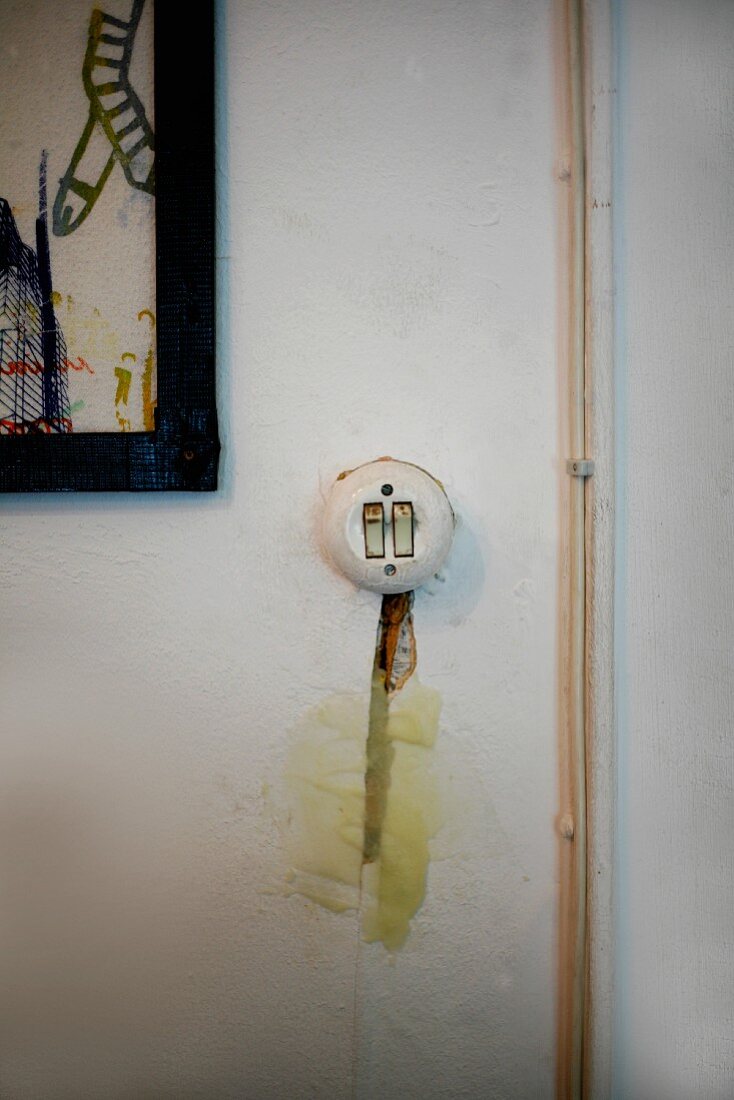 Vintage Lichtschalter und Schlitz mit Kartoffelbrei-Putz neben Aufputz-Kabeln