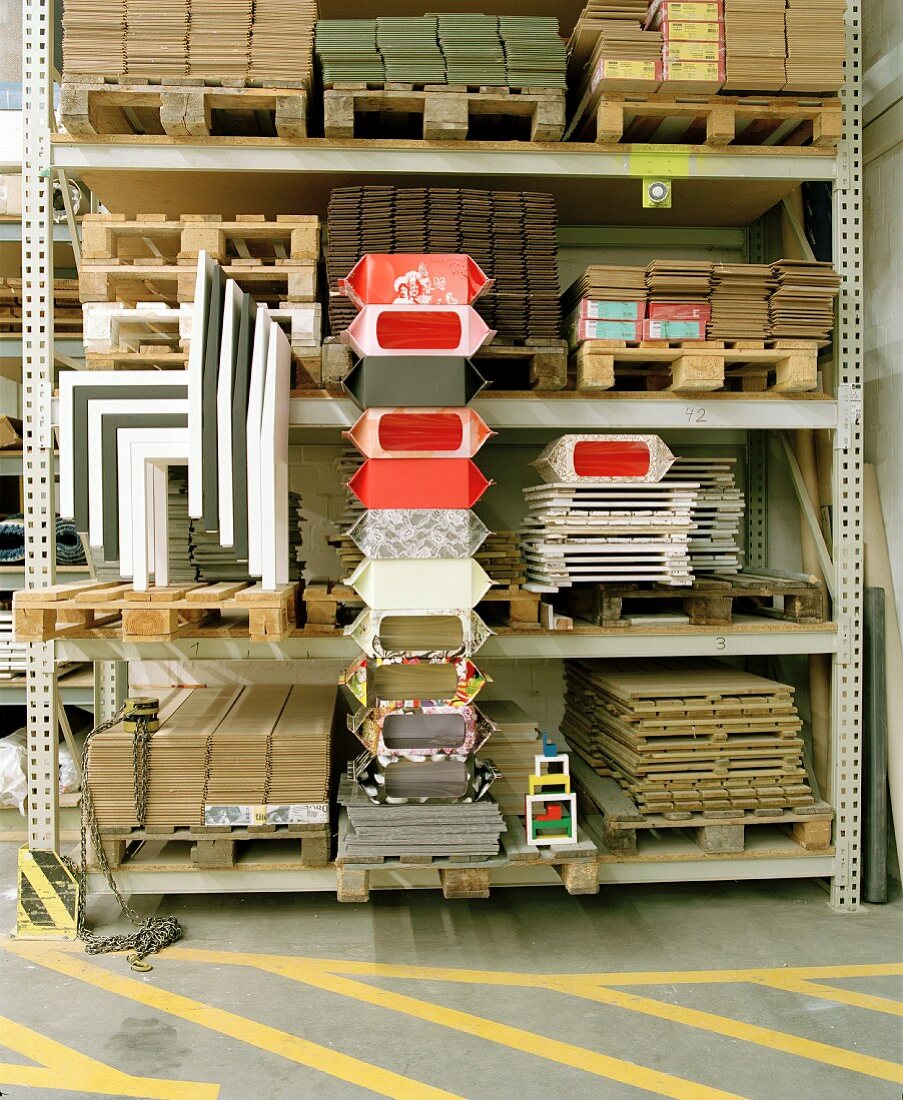 Metal warehouse shelves of wooden pallets and storage boxes next to modern nesting chairs