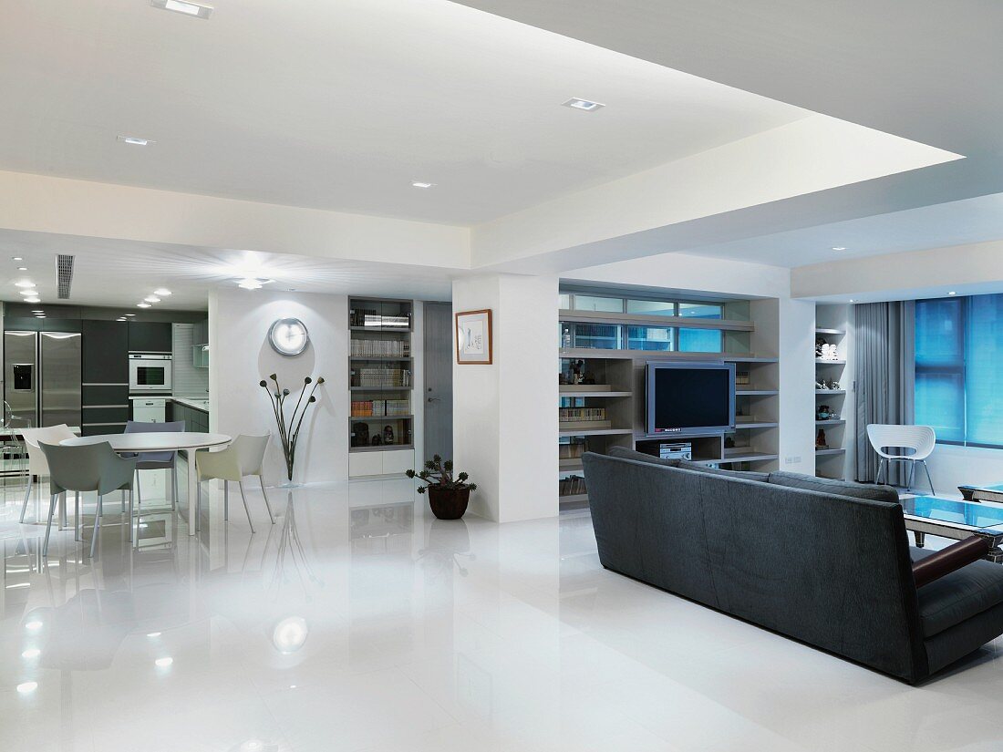 Modern living and dining room with a gray sofa on a glossy white floor