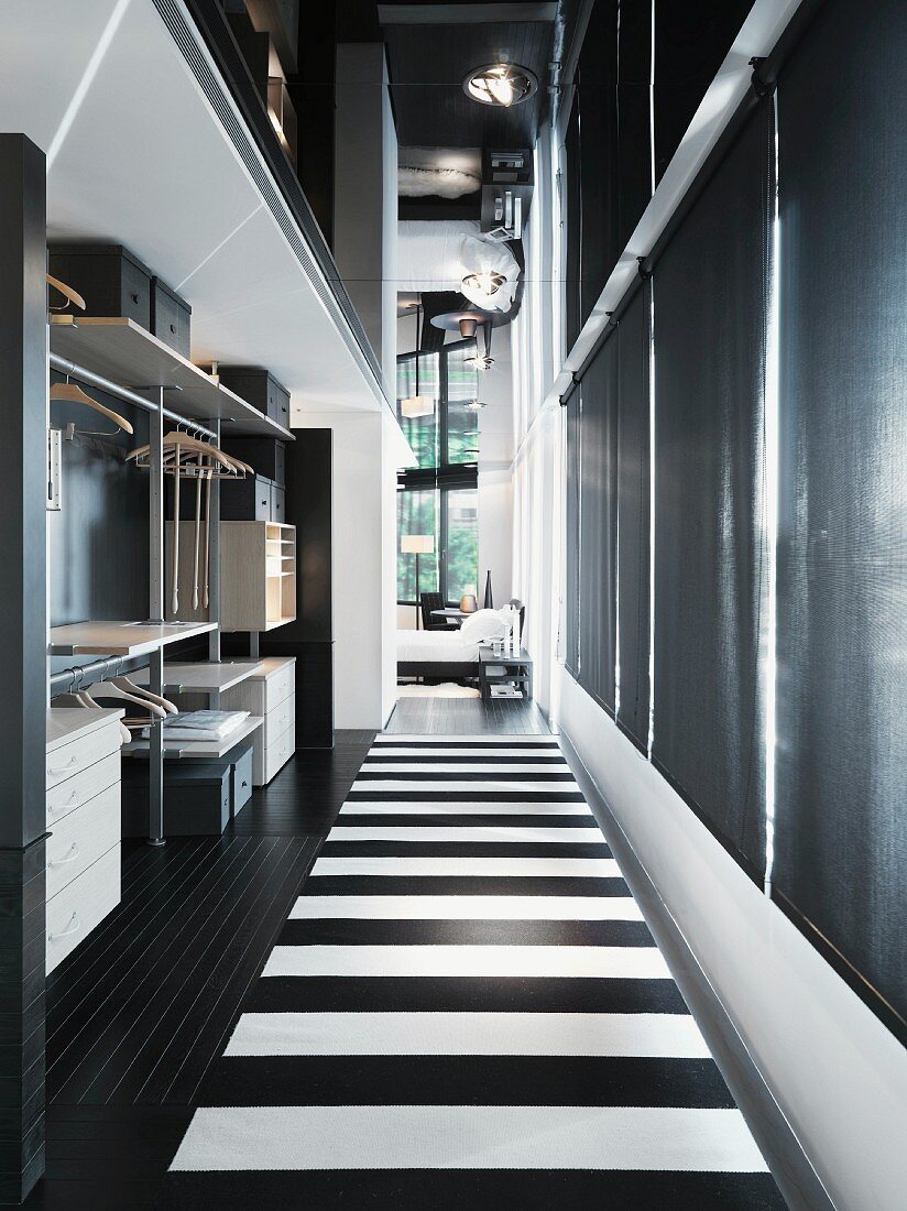 Offene Garderobe und Boden mit schwarz weissen Streifen im Gangbereich eines loftartigen Wohnraumes