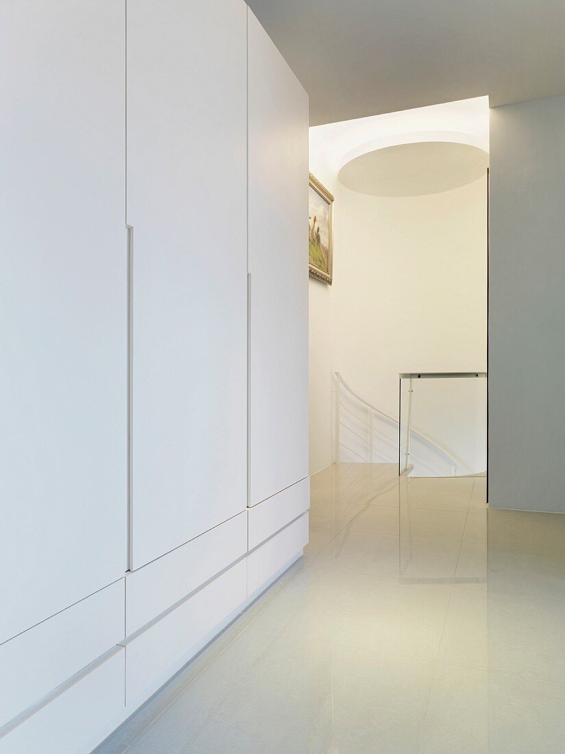Weisser Garderobenschrank in modernem Vorraum und Blick auf Treppenabgang
