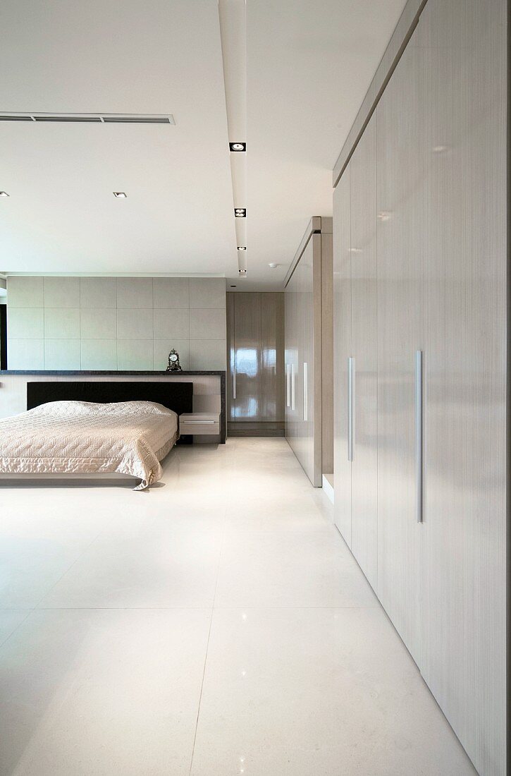 Minimalistisches Schlafzimmer mit Einbauschränken und abgehängtem Deckenfeld mit Beleuchtung