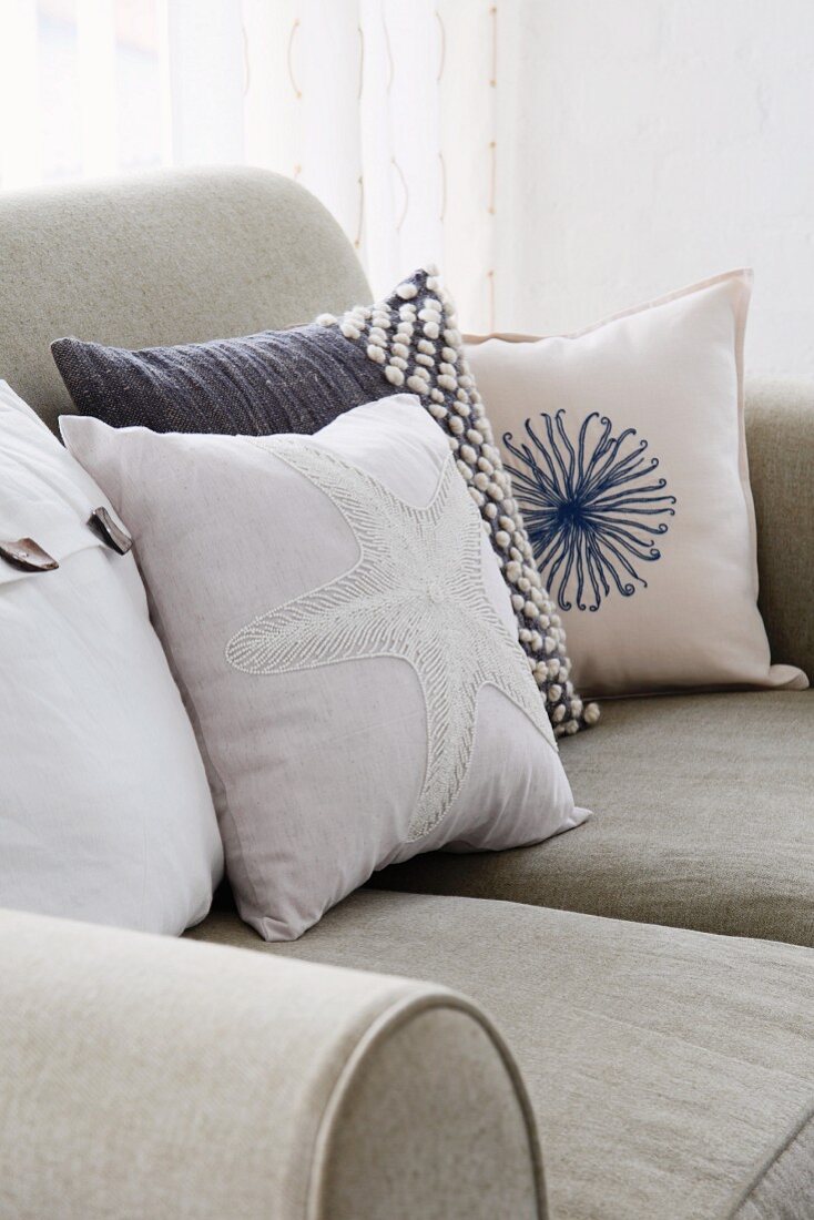 Various scatter cushions in maritime style on sofa with stone grey linen upholstery