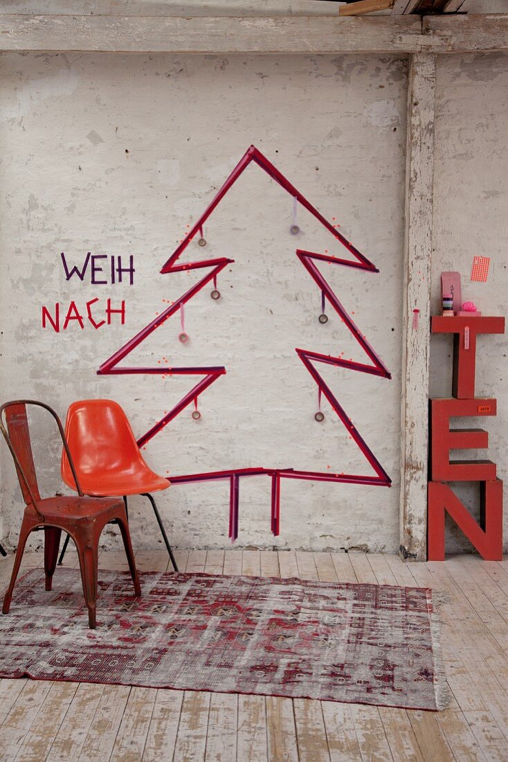 Retro chairs in front of Christmas tree sketched on wall in rustic interior