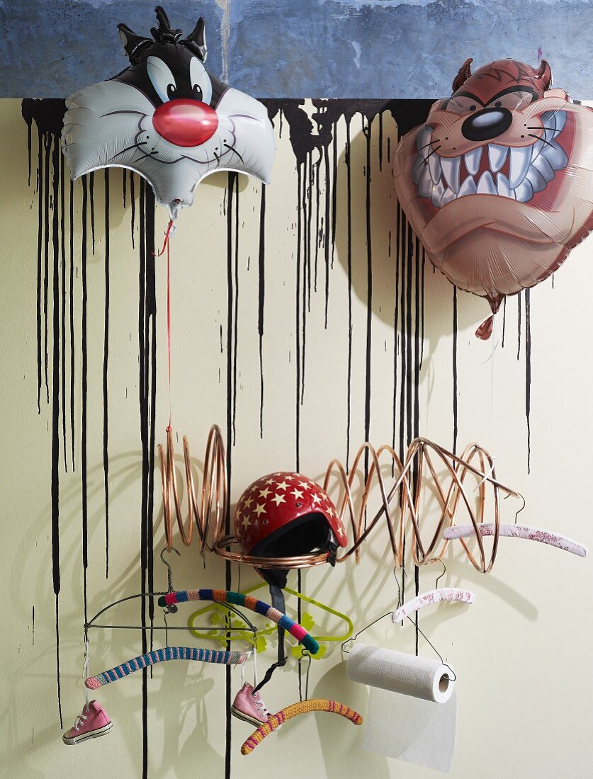 Moderne Garderobe mit verschiedenen Kleiderbügeln & dekoriert mit Luftballons mit Comicmotiven