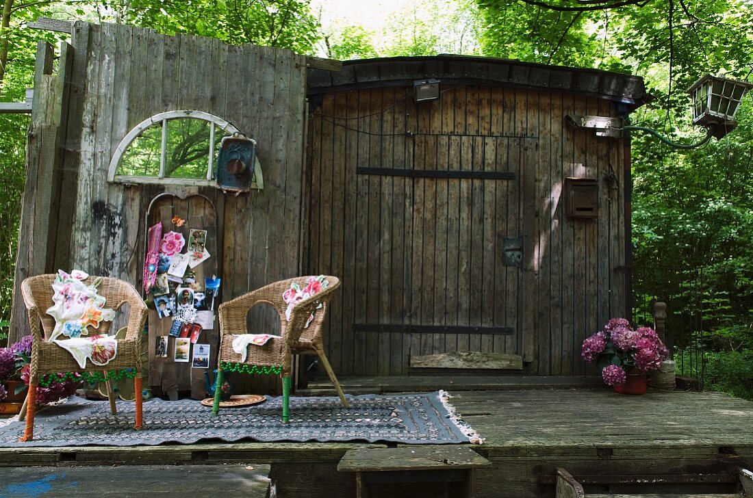 Wicker chairs on patterned rug in front of postcards pinned to old barn wall