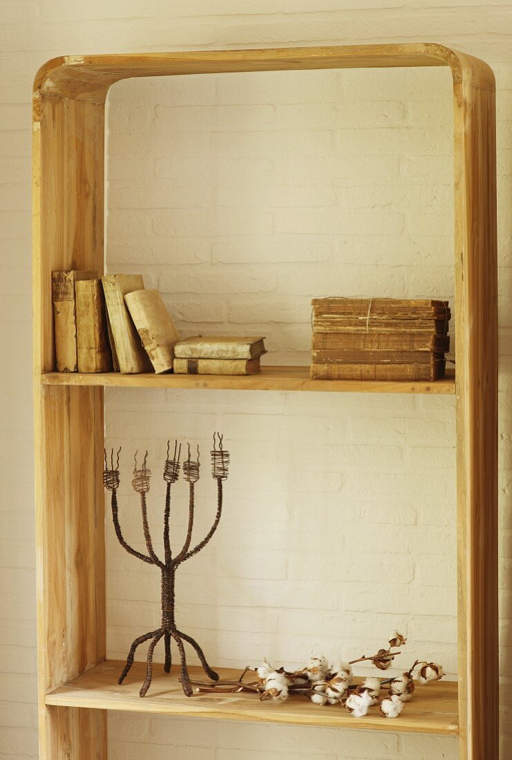Antiquarische Bücher und Vintage Kerzenständer in rustikalem Holzregal vor geweisselter Ziegelwand