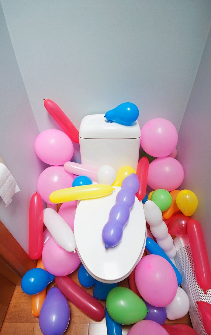 Viele bunte Luftballons in einem Toilettenraum