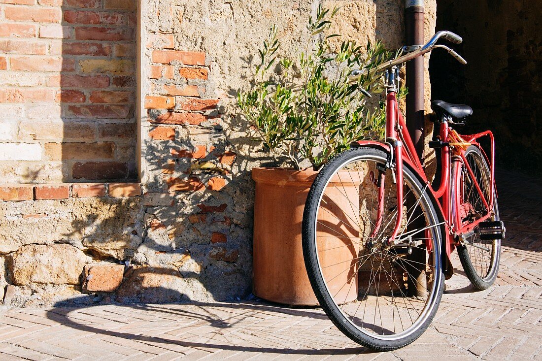 Fahrrad lehnt an einer großen Terrakottavase in der Sonne