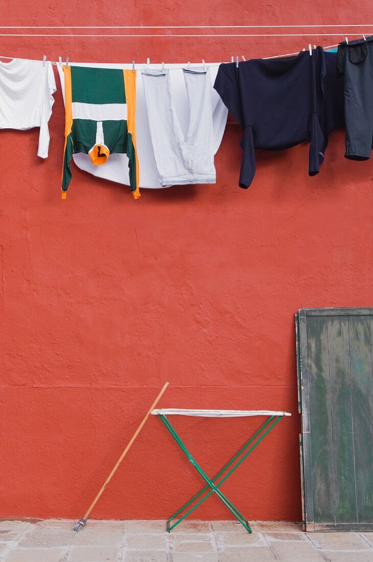 Wäsche hängt an der Leine vor roter Hauswand