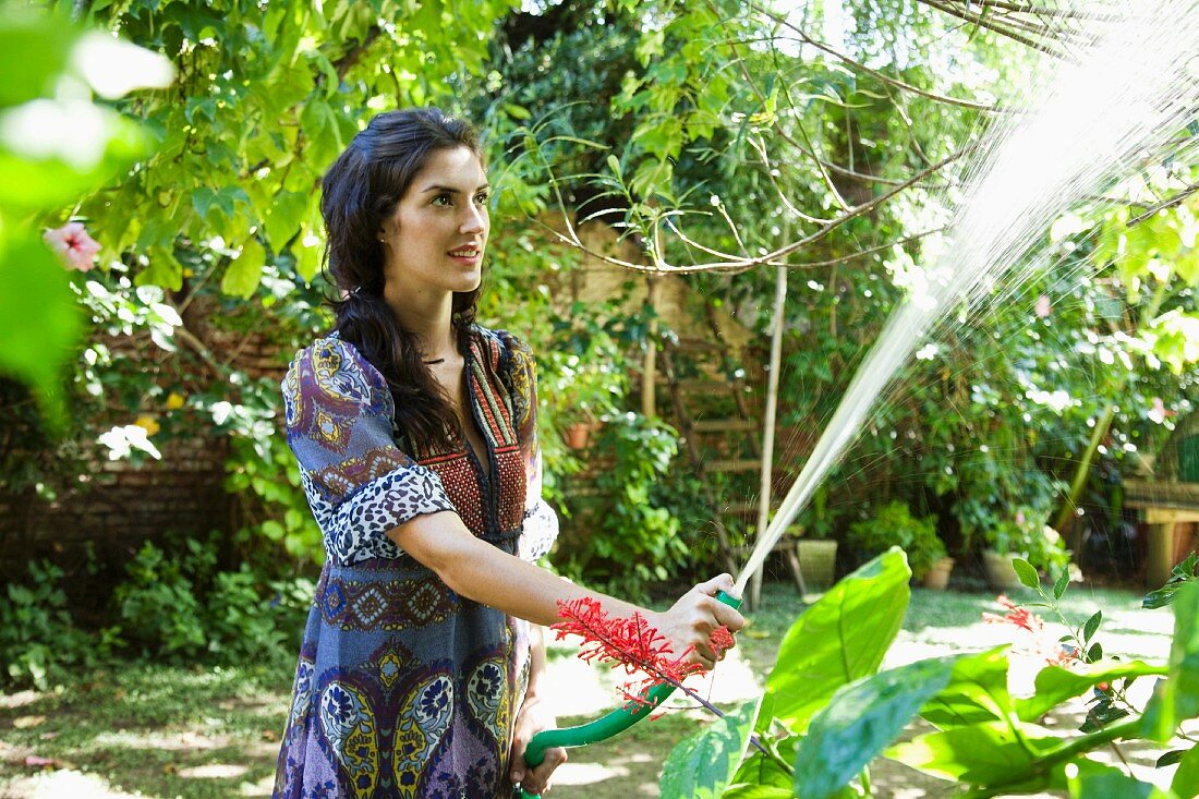 Frau giesst Pflanzen im tropischen Garten