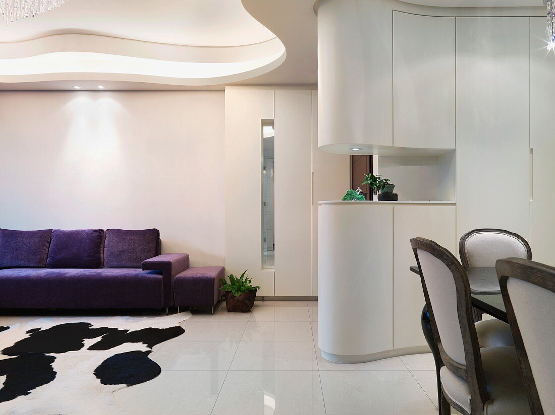 Offener Wohnraum mit amorpher Deckengestaltung und Essplatz vor Schrank als Raumteiler