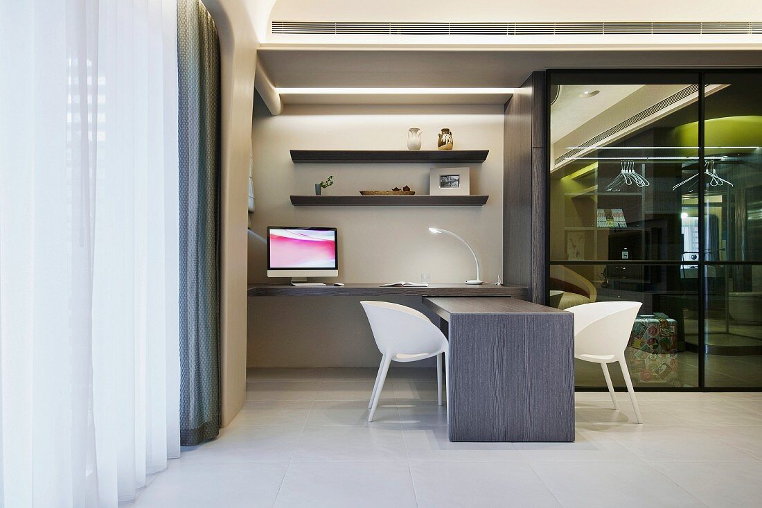 White shell chairs by a modern desk next to a glass wall