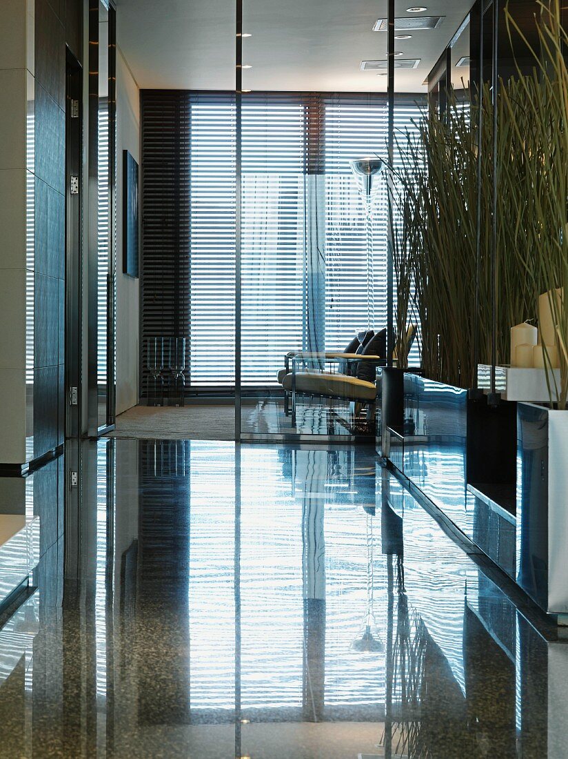 Lobby with a highly polished stone floor and view through a glass wall partition of armchairs