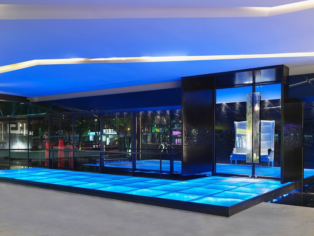 Überdachter Eingangsbereich mit beleuchteten Glaspaneelen auf Boden
