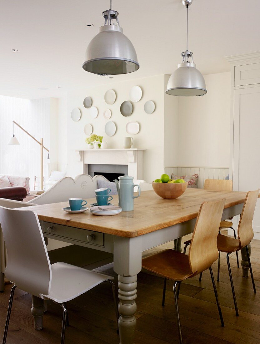 Rustikaler Küchentisch mit modernen Stühlen unter Industrieleuchten in ländlichem Wohnraum
