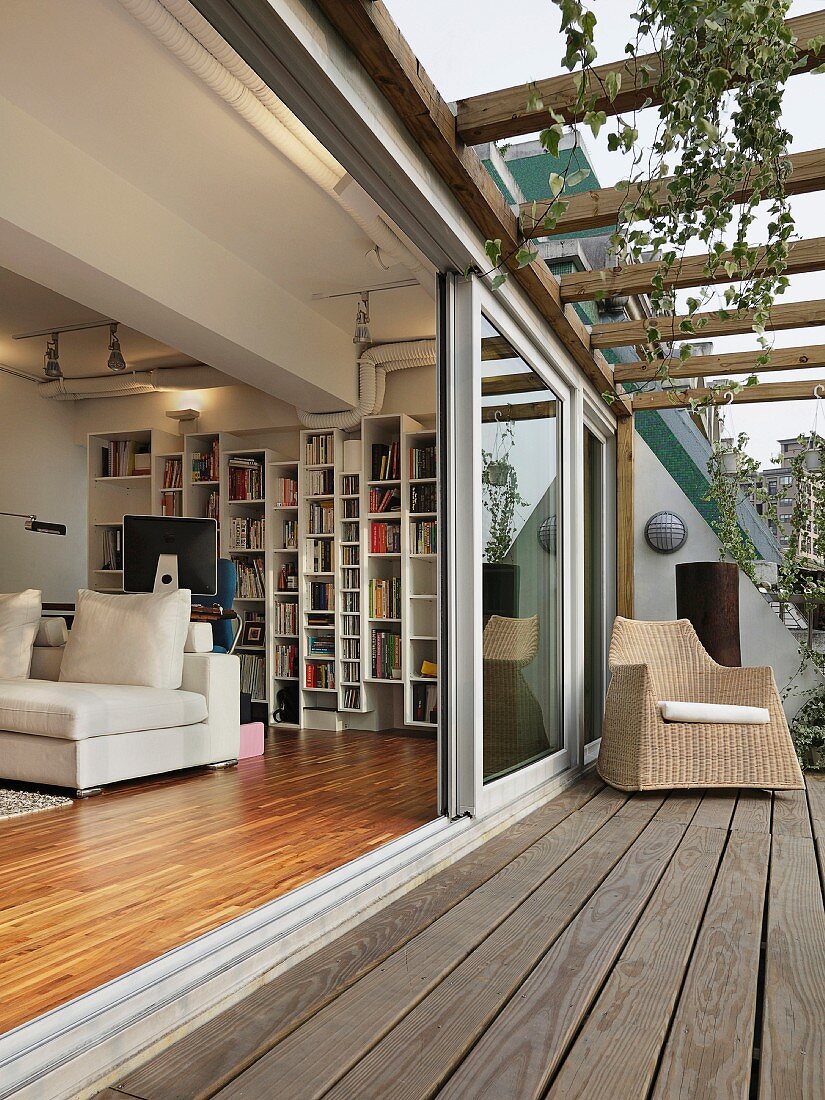 Blick von der Terrasse in das moderne Wohnzimmer mit Panoramafenster und offener Installationsebene an der Decke