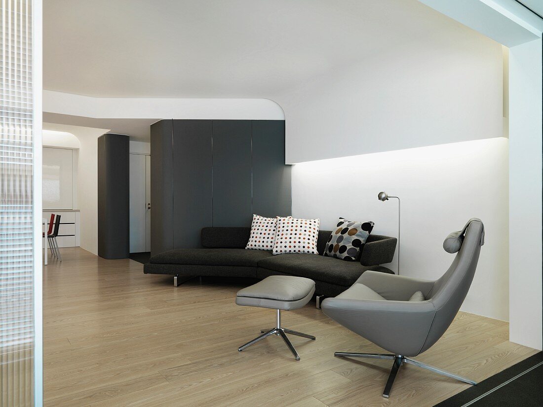 Designer sofa and armchair in a modern living room with suspended ceiling and indirect lighting