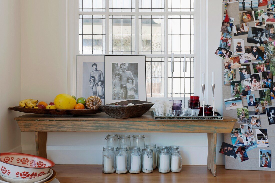 Obstschalen, Salzbehälter und Tischdeko auf einer alten Holzbank neben einer Fotowand