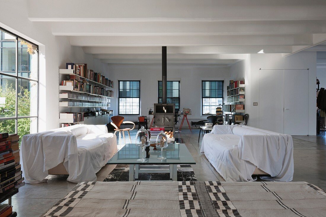 Covered sofas by a glass coffee table in a modern loft