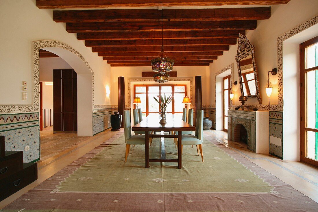 Moderne Esszimmergarnitur au einem großen Teppich im rustikalen Raum mit Holzbalkendecke und orientalischem Flair