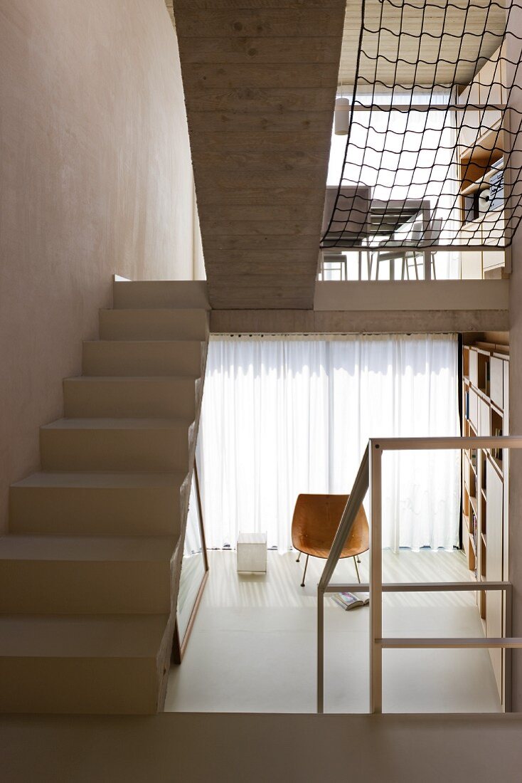 Various living areas in open-plan, split-level interior with staircase in contemporary building