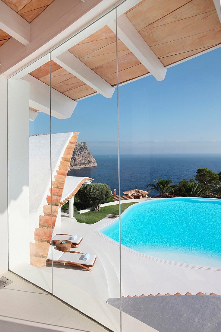 Ein Panoramafenster eröffnet den Blick über die Terrasse mit Pool auf das Meer