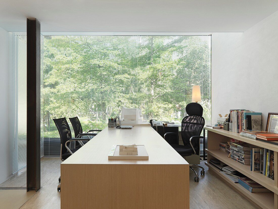 Arbeitstisch aus hellem Holz vor Panoramafenster