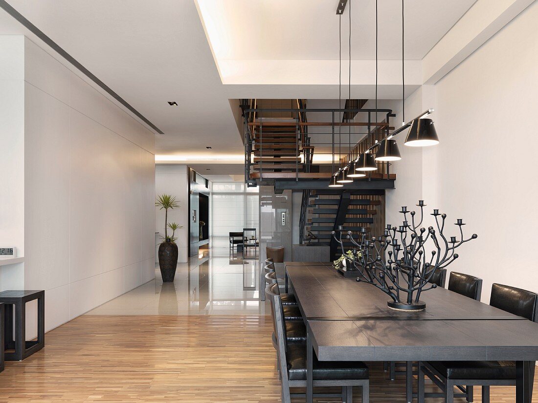 Esstisch aus dunklem Holz in offenem Wohnraum mit wechselndem Bodenbelag und Blick auf Treppe