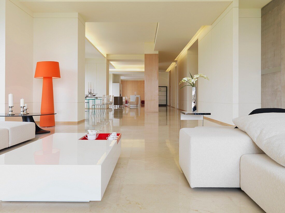 weiße Sitzmöbel und orangefarbene Stehlampe in offener Designerwohnung