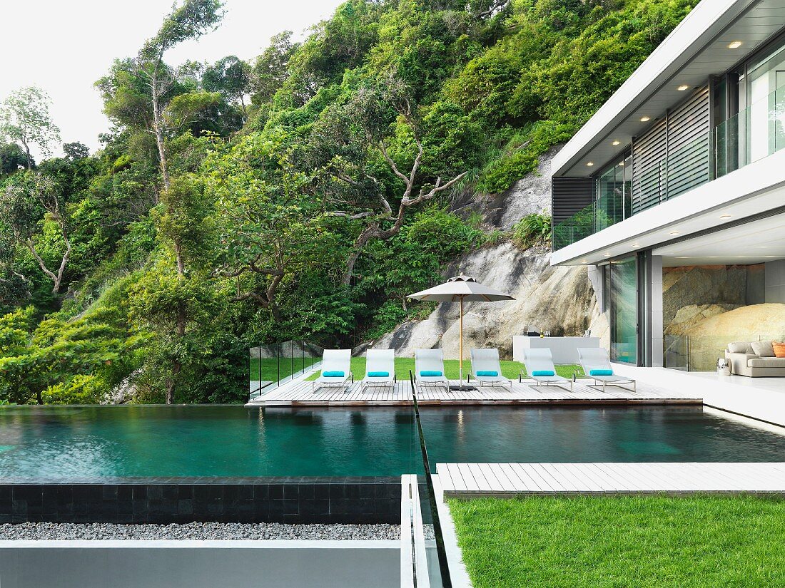 Pool outside modern home with row of lounge chairs
