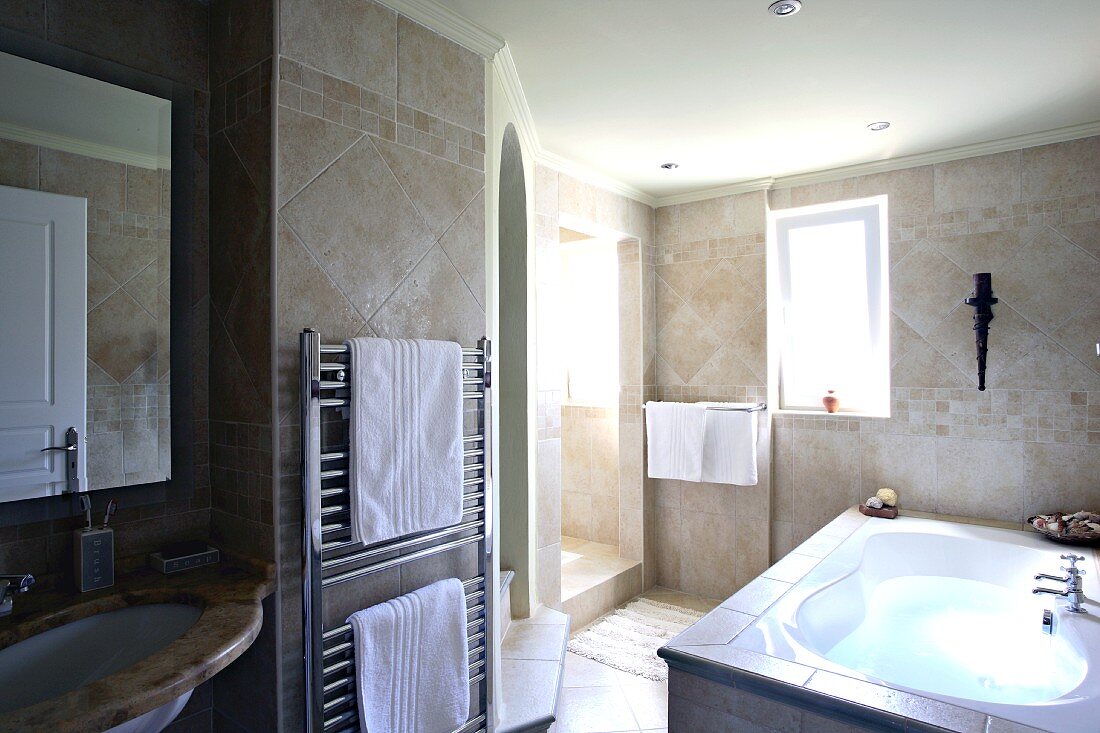 Verfliestes Badezimmer mit Badewanne, Waschbecken und Heizkörper mit Handtüchern (Villa Octavius, Lefkas, Griechenland)