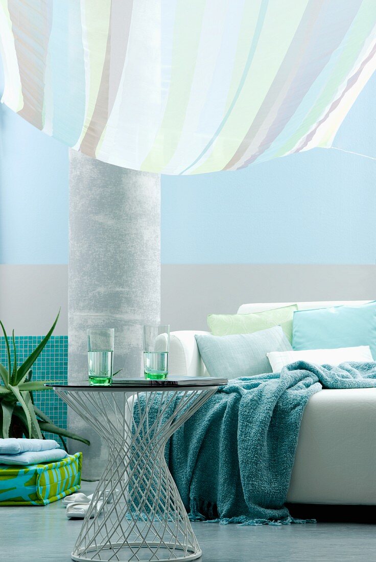 Living area in shades of aqua with sofa and side table below striped awning