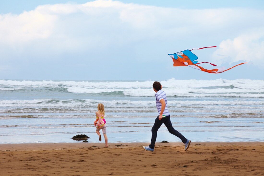 Vater und Tochter lassen am Strand Drachen steigen
