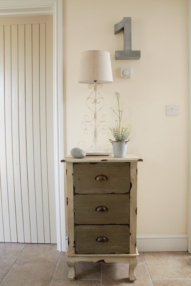 Vintage chest of drawers against pale wall in hallway