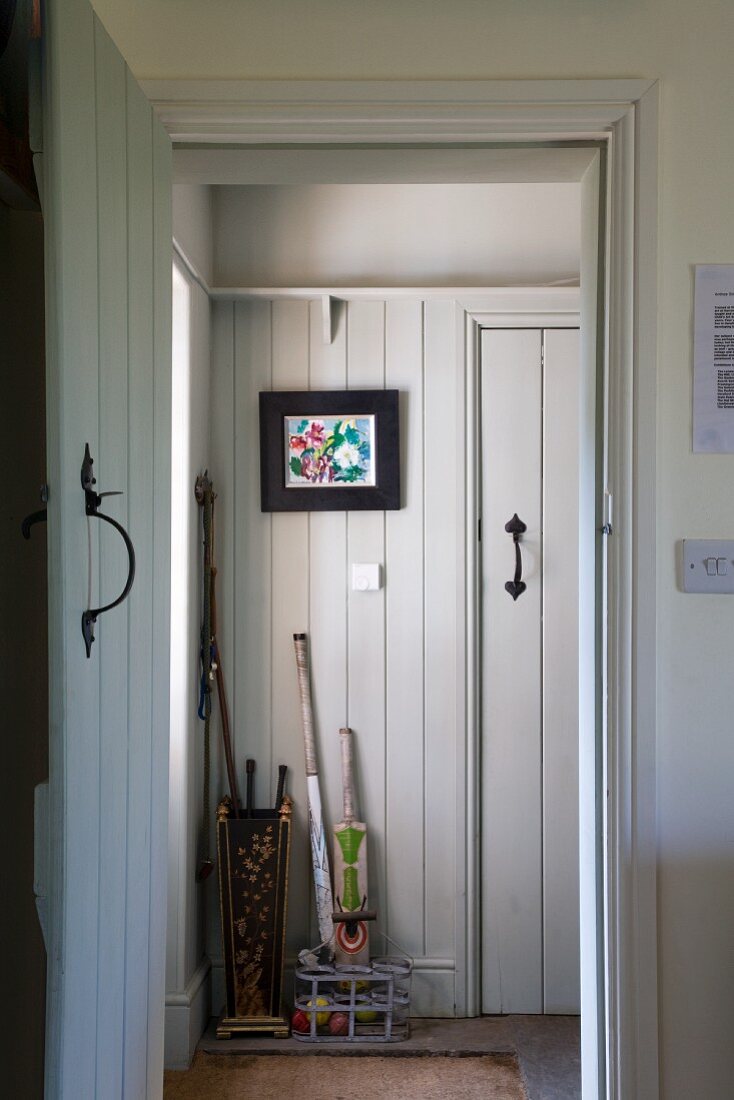 View through open door into rustic foyer with white wood-clad walls