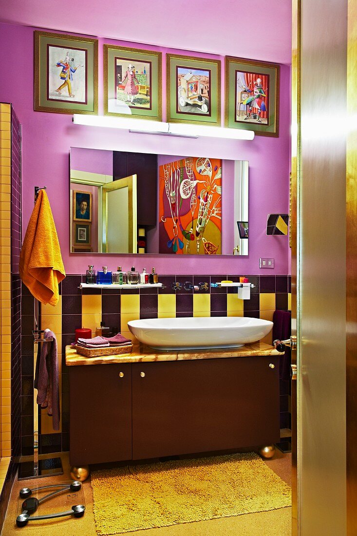 Cheerful bathroom in warm shades with collection of artworks and large painting reflecting in mirror