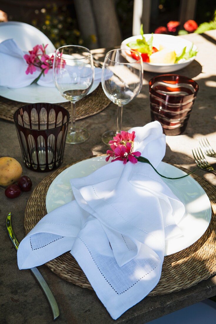 weiße Stoffserviette mit Blumendeko auf rustikal gedecktem Tisch