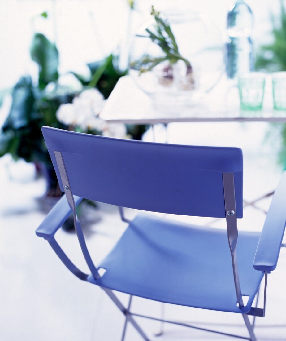 Moderner Klappstuhl aus blauem Kunststoff vor schlichtem Tisch